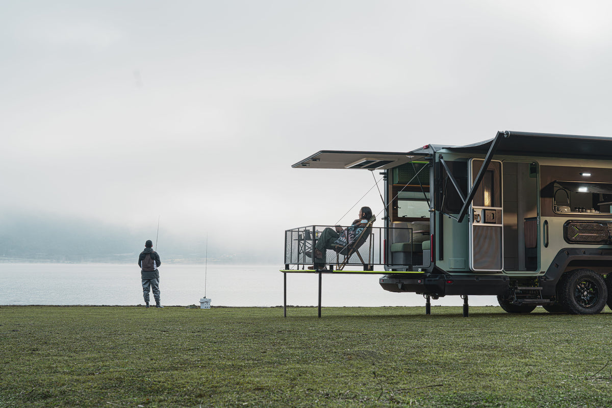 Evotrex PG5 campsite beside a lake with its rear deck open and two people fishing